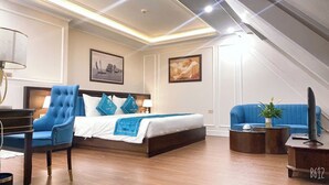 A modern hotel room with a large bed, a blue armchair, a sofa, and a small coffee table. - Ruby Queen Hotel (Bai Chay)