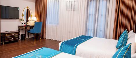 A hotel room with two beds, a desk with a chair, a TV, and curtains.