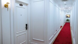 A hallway with white doors, a red carpet, and a framed picture on the wall. - Ruby Queen Hotel (Bai Chay)