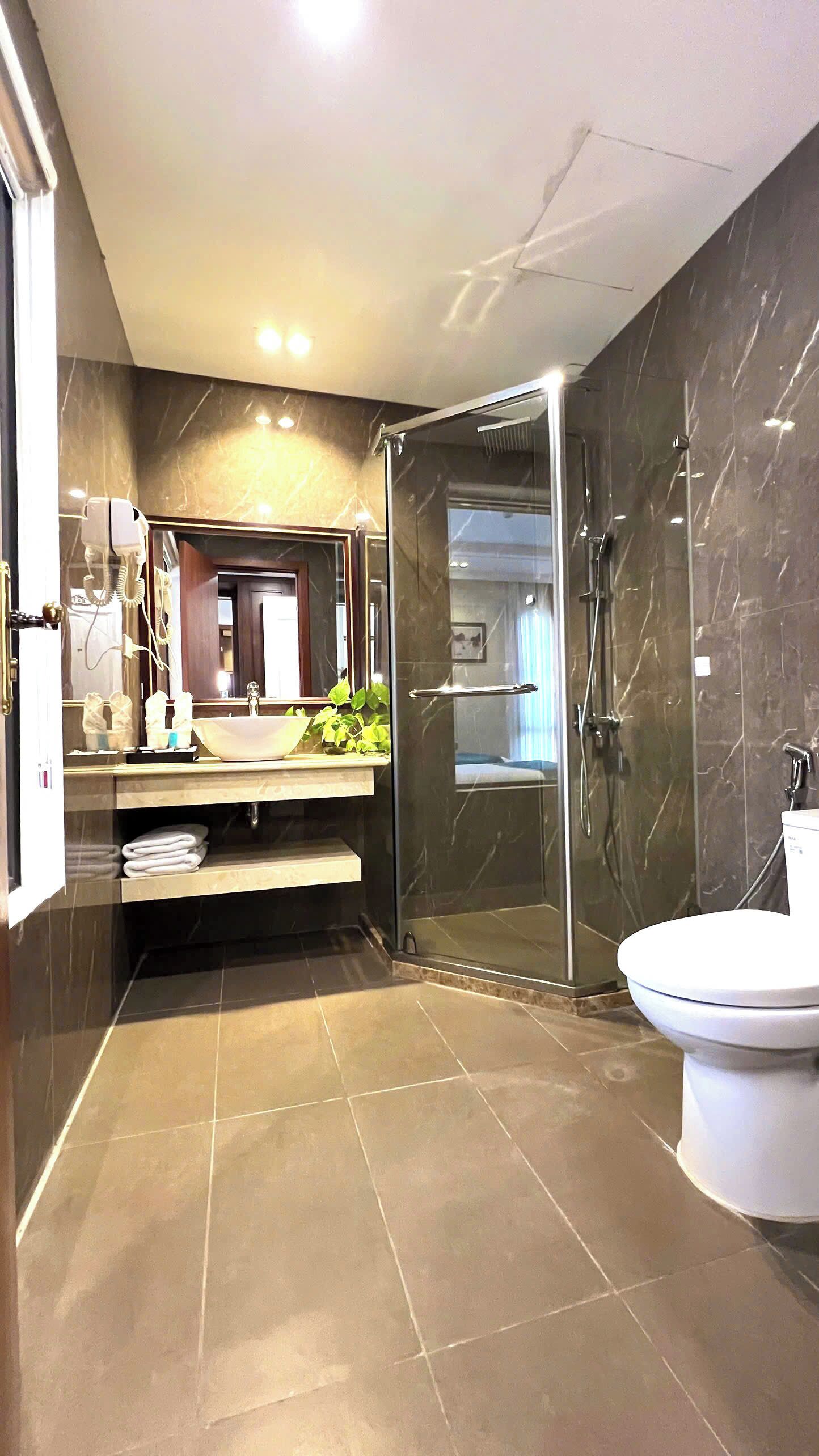 A modern bathroom with a glass-enclosed shower, a white sink, and a large mirror.