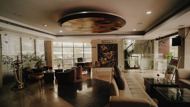 A spacious lobby with a modern design, featuring a large seating area, a decorative ceiling, and large windows allowing natural light. - Joance Regency (Thodupuzha)