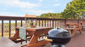 A wooden deck with picnic tables, a barbecue grill, and wine glasses. - Taean Vintage House Pet-friendly Pension (Taean)