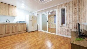 Una cocina con armarios de madera, un refrigerador, una estufa y un ventanal corredizo que da a un balcón.