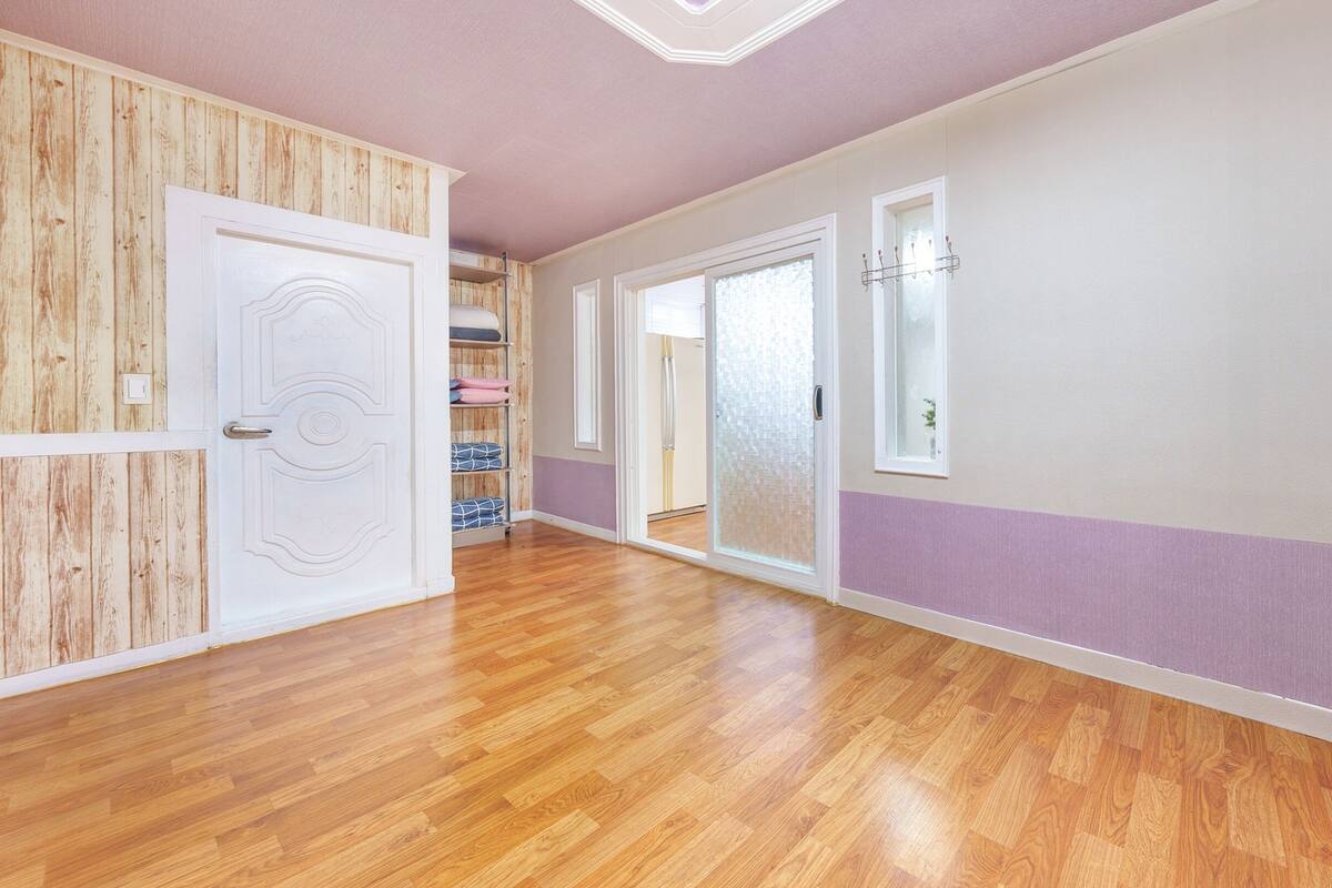 Un pasillo con piso de madera, puertas blancas y una pared de acento púrpura.