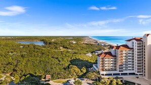 A coastal hotel with multiple floors, a parking area, and a view of the beach and ocean.