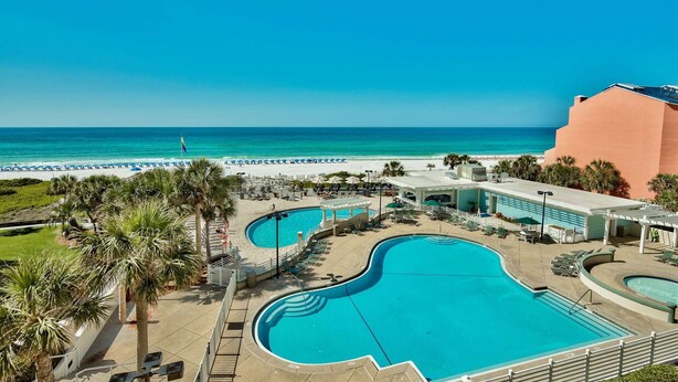 A resort with multiple swimming pools, a beach, and a view of the ocean.
