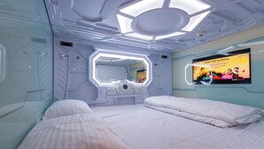 Habitación de hotel moderna con cama, espejo y televisor empotrado mostrando un anuncio.