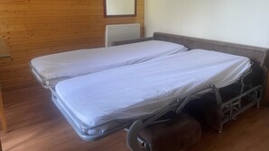 A room with two single beds, a wooden wall, a white radiator, and a red object on the wall. - Hameau 3 103 - SPA & Piscine Appartement 6 Pers (Orelle)
