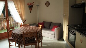 A cozy kitchen with a dining table, chairs, a sofa, and a stove. - Quiet Apartment in Nature (Chatel)