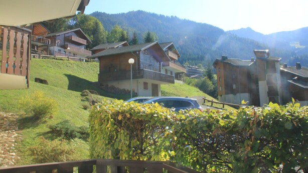 A hillside residential area with houses featuring balconies and a car parked nearby. - Quiet Apartment in Nature (Chatel)