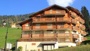 A multi-story building with balconies, situated on a hillside with a clear sky. - Quiet Apartment in Nature (Chatel)