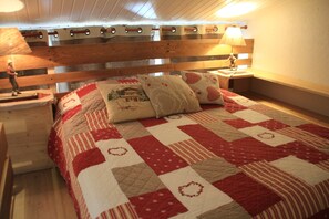 A bedroom with a wooden headboard, a quilted bedspread, and bedside lamps.