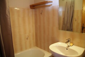 A bathroom with a bathtub, a sink, and a mirror.
