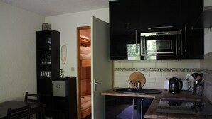 Cocina compacta con microondas, lavamanos y un pequeño comedor.