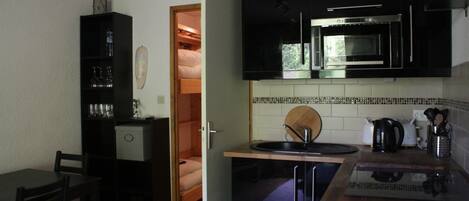 A compact kitchen with a microwave, sink, and a small dining area.