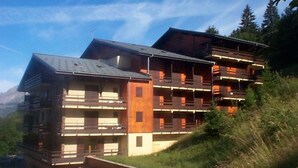 Un edificio de varios pisos con balcones, con montañas al fondo.