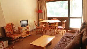Un accogliente soggiorno con un tavolo in legno, sedie, un divano e una televisione.