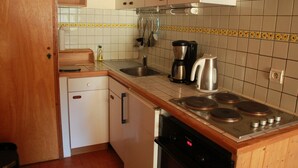 Una cucina compatta con lavastoviglie, fornello e moka.
