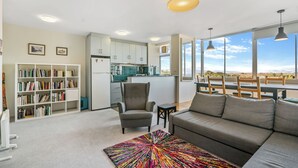 A modern living room with a sofa, a bookshelf, a small table, and a colorful rug. - Marine Magic (St Kilda)