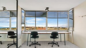 A corner office with a desk, two chairs, and a view of a coastal landscape. - Marine Magic (St Kilda)