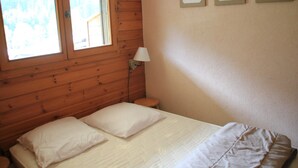 A bedroom with a wooden headboard, a bed with white bedding, a bedside lamp, and framed heart decorations on the wall. - Voinettes Vnb8 Telecabine & Mountain 4 Pers (Chatel)