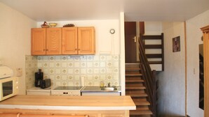 A kitchen with wooden cabinets, a microwave, a toaster, and a tiled backsplash. - Tavaillons Tv31 Swimming Pool & Center 4 Pers (Chatel)