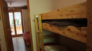 A room with a bunk bed, a door leading to a balcony, and a red chair. - Voinettes Vnb2 Telecabine & Mountain 4 Pers (Chatel)