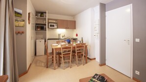 A compact kitchen with a microwave, a small refrigerator, and wooden chairs around a dining table. - Balcons C 001 - Parc Nat. Vanoise Appart. 5 Pers (Val-Cenis)
