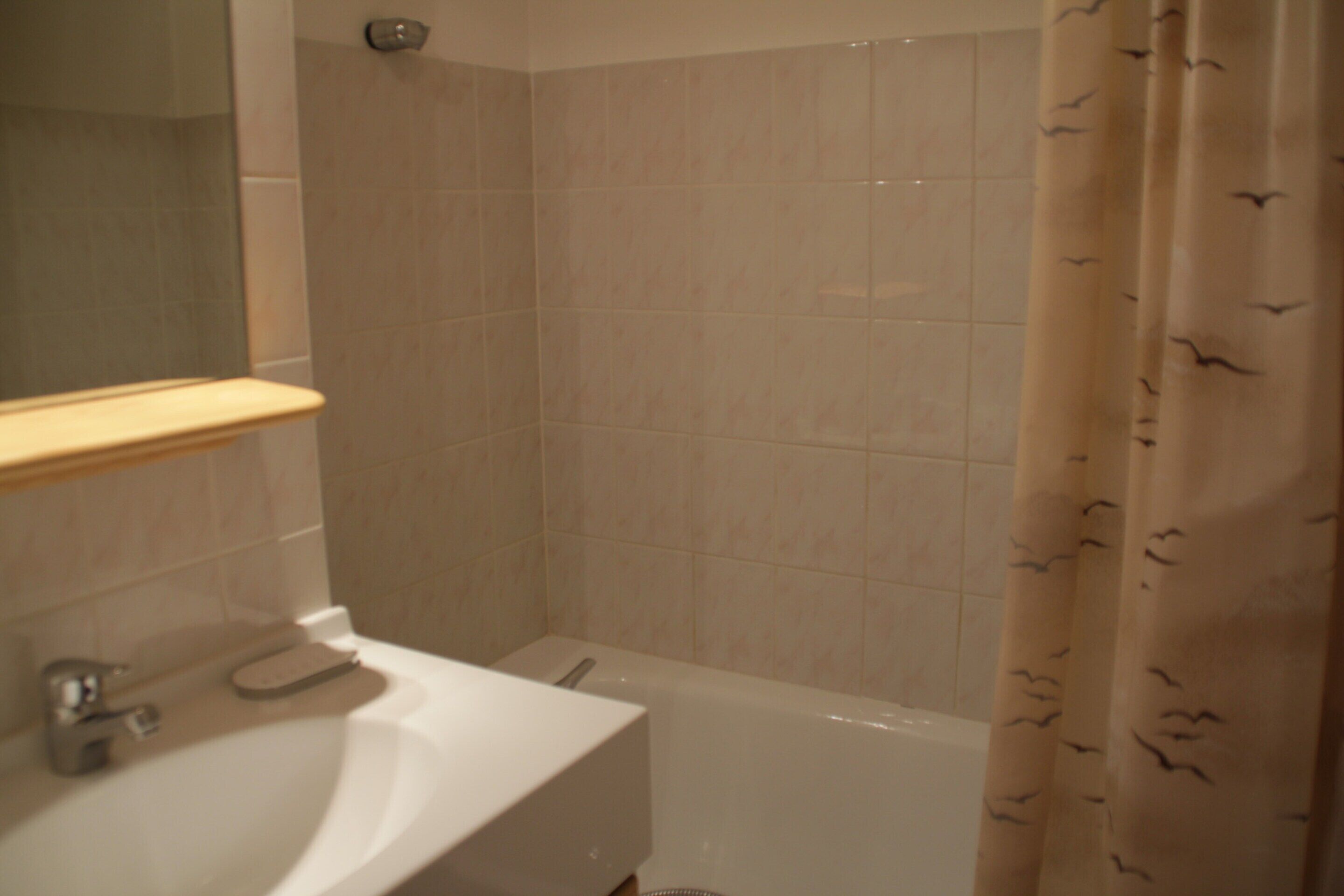 A bathroom with a sink, mirror, and shower area.