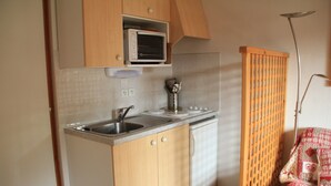 Una cocina compacta con microondas, lavaplatos y fregadero.