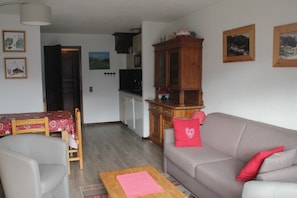 Un salon comprenant un canapé, un meuble en bois, un téléviseur et un coin repas avec une table et des chaises.