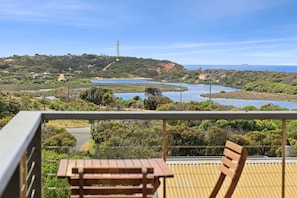 Ein Balkon mit Blick auf eine Küstenlandschaft, darunter ein Leuchtturm, ein Fluss und hügeliges Gelände.
