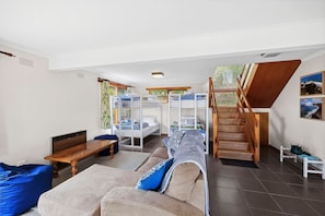 A modern interior with a sofa, a wooden table, a bunk bed, and a staircase.