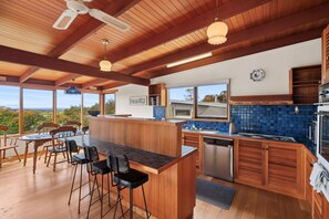 A modern kitchen with wooden beams, a bar area, and a view of the outdoors. - Banksia Haven (Fairhaven)