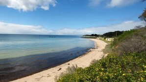 A beach with clear water, a sandy shore, and some greenery.