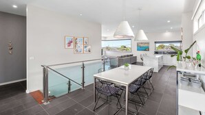 A modern kitchen with a dining area, a staircase, and a view of the outdoors.