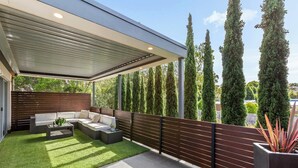 A covered patio with a sectional sofa, a coffee table, and a small plant.