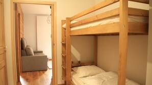 Una stanza con un letto a castello, una poltrona letto e un pavimento in legno.