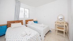 A bedroom with two beds, a wooden dresser, a mirror, and a window with curtains. - GE Harbour Apartment 24 (Polis)