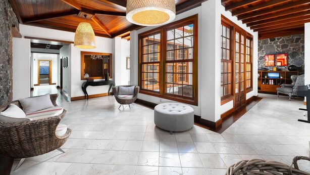 Un hall amplio con ventanas grandes, una chimenea de piedra y una zona de estar moderna.