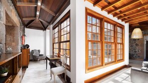 Una habitación amplia con ventanas grandes, pared de piedra y techo de madera.