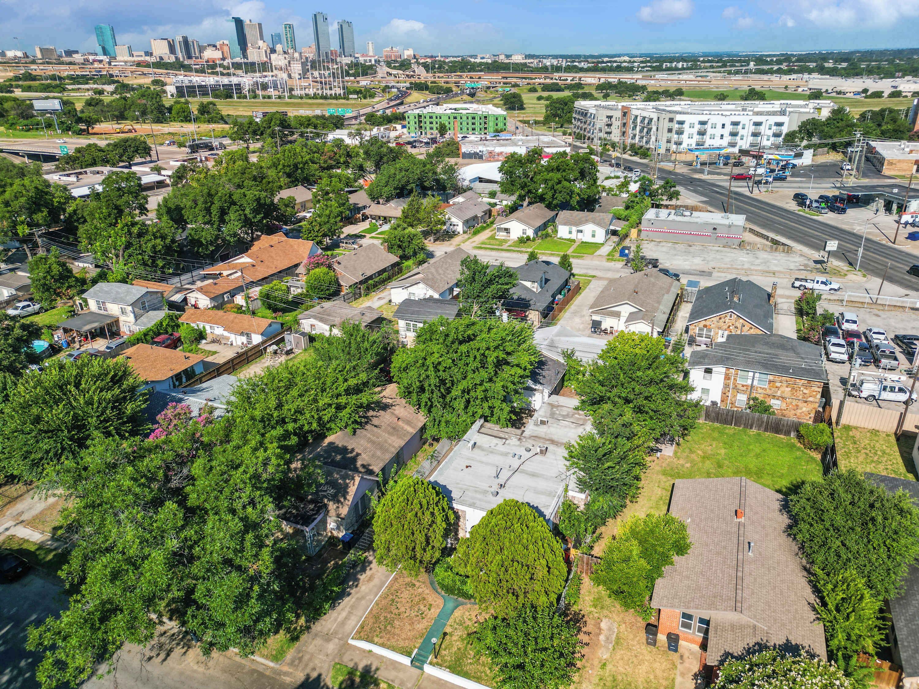 Luchtbeeld van een woongebied met huizen, wegen en een verafgelegen stadsachtergrond.