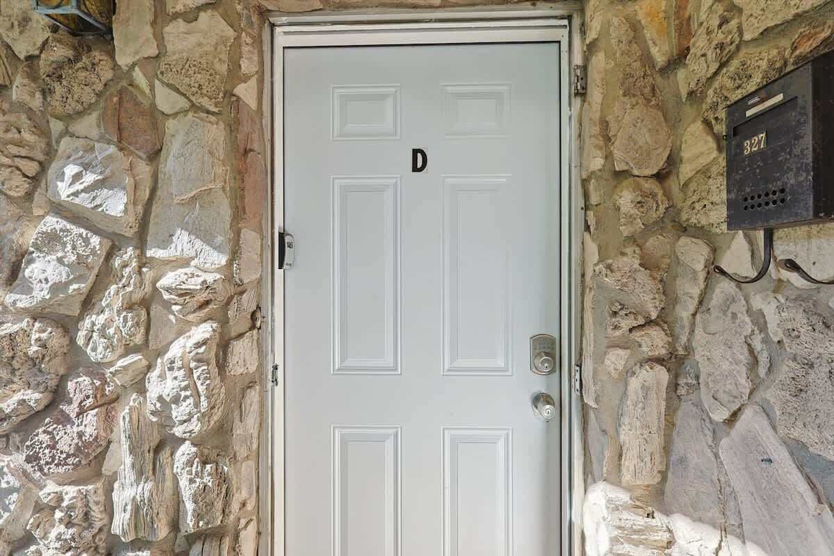 Una porta bianca con la lettera 'D' sopra, incastonata in un muro di pietra.
