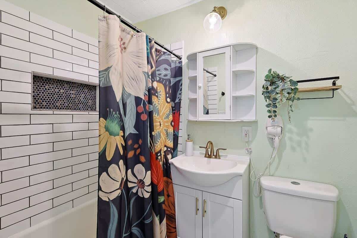 A bathroom with a white sink, a toilet, and a shower curtain with floral patterns.