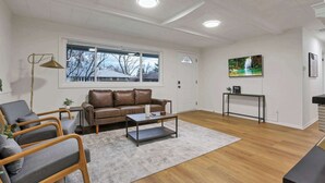 A living room with a sofa, armchairs, a coffee table, a TV, and a window with a view. - The Reynoldsburg Getaway (Reynoldsburg)