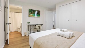 A bedroom with a bed, a desk, a chair, a shower, and a door. - The Reynoldsburg Getaway (Reynoldsburg)
