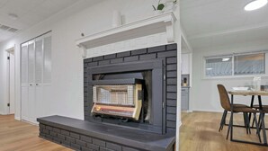 A modern living room with a fireplace, a dining area with chairs, and a window with curtains. - The Reynoldsburg Getaway (Reynoldsburg)