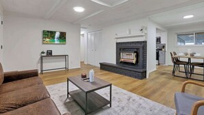 A modern living room with a fireplace, a dining area, and a kitchen in the background. - The Reynoldsburg Getaway (Reynoldsburg)