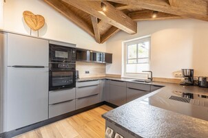 Una cocina moderna con gabinetes grises, horno integrado y una isla grande con fregadero.