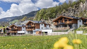 A row of wooden chalets with balconies, set against a mountainous backdrop. - Superior Ferienhaus # 2B mit Sauna (Uttendorf)